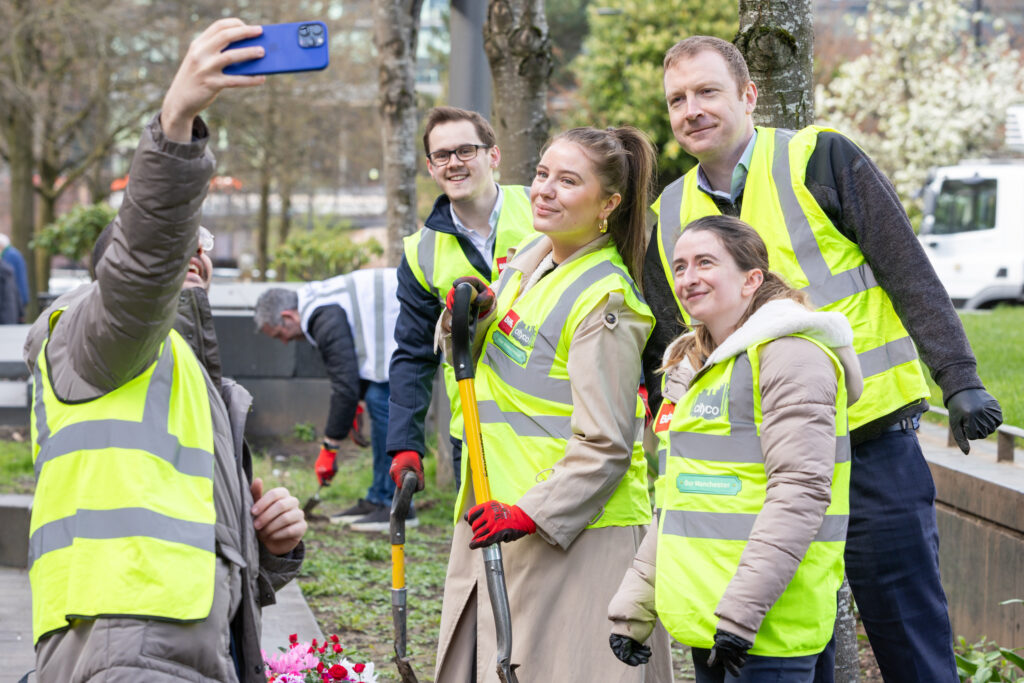 Group wearing high-visibility vests taking a selfie during outdoor spring cleaning