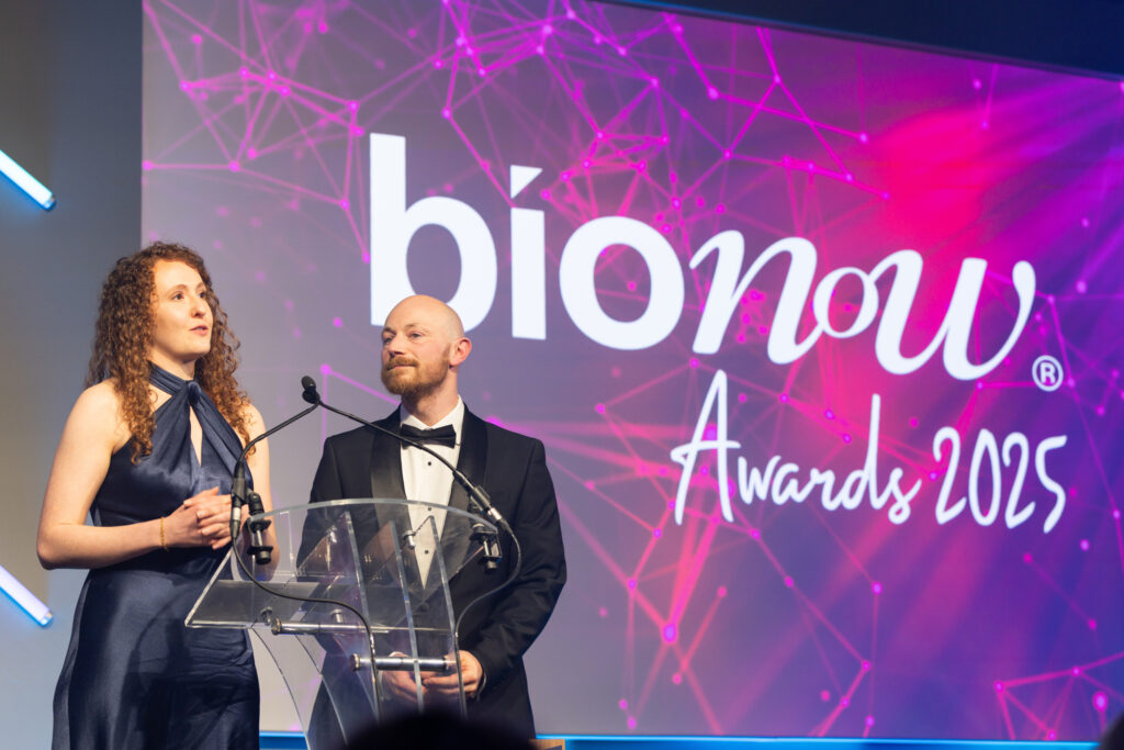 Woman and man in formal clothes speaking on stage at BioNow Awards 2025